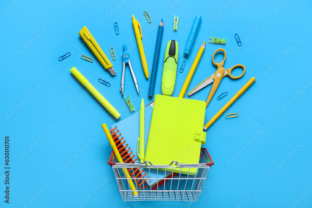 Shopping basket with different stationery on blue background