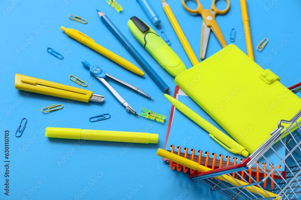 Shopping basket with different stationery on blue background