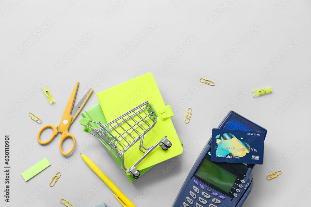 Payment terminal, credit card and shopping cart with different stationery on grey background