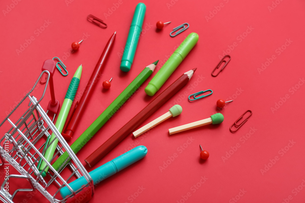 Shopping cart with different stationery on red background