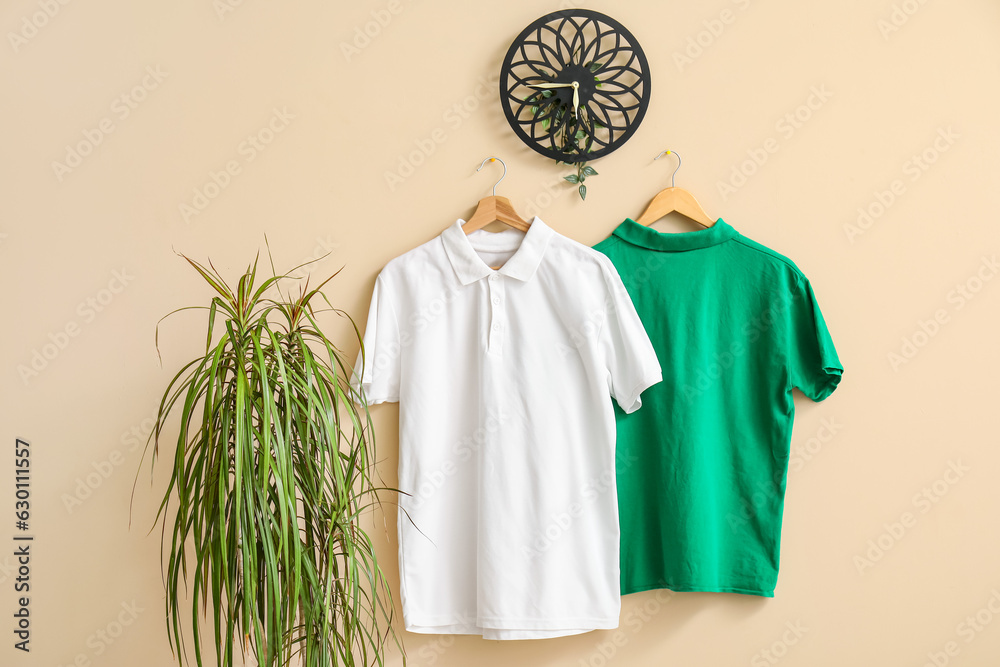 Stylish t-shirts hanging on beige background