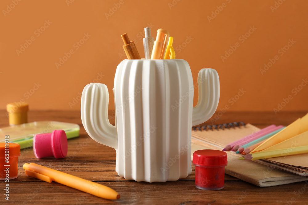 Stylish holder with different stationery on wooden table