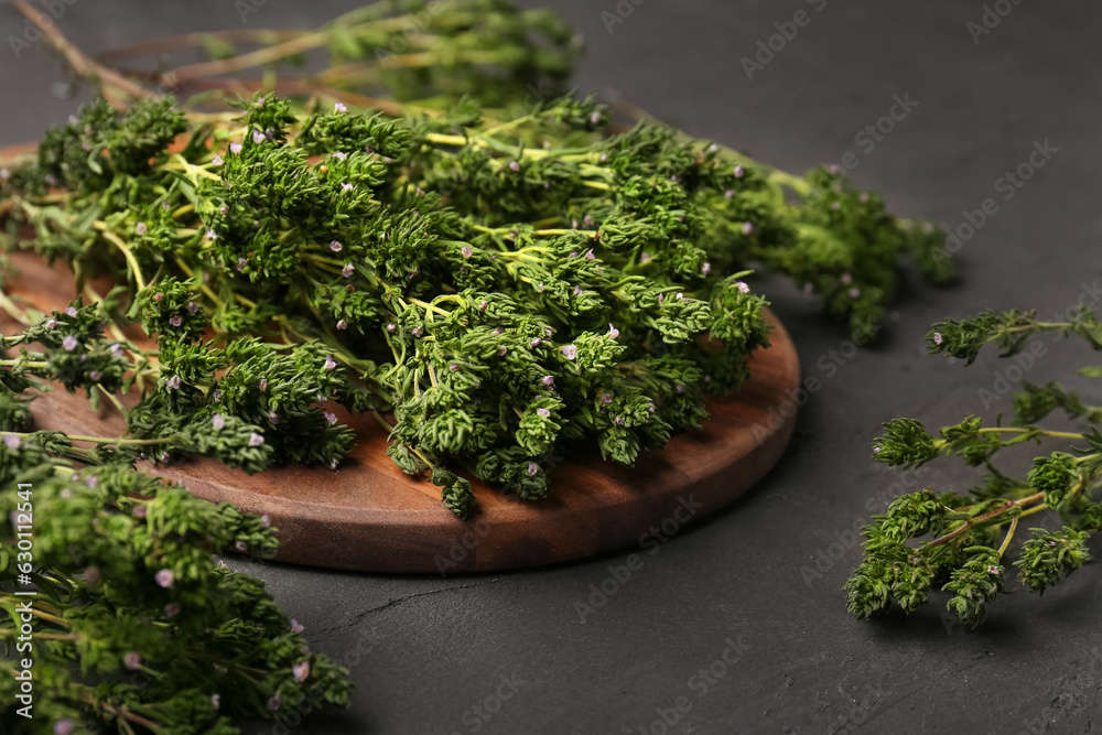 Wooden board with fresh thyme on dark background, closeup