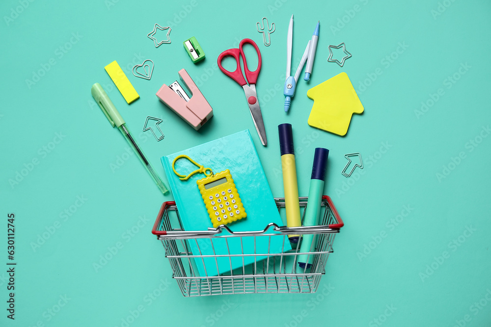 Composition with shopping basket and different stationery on color background