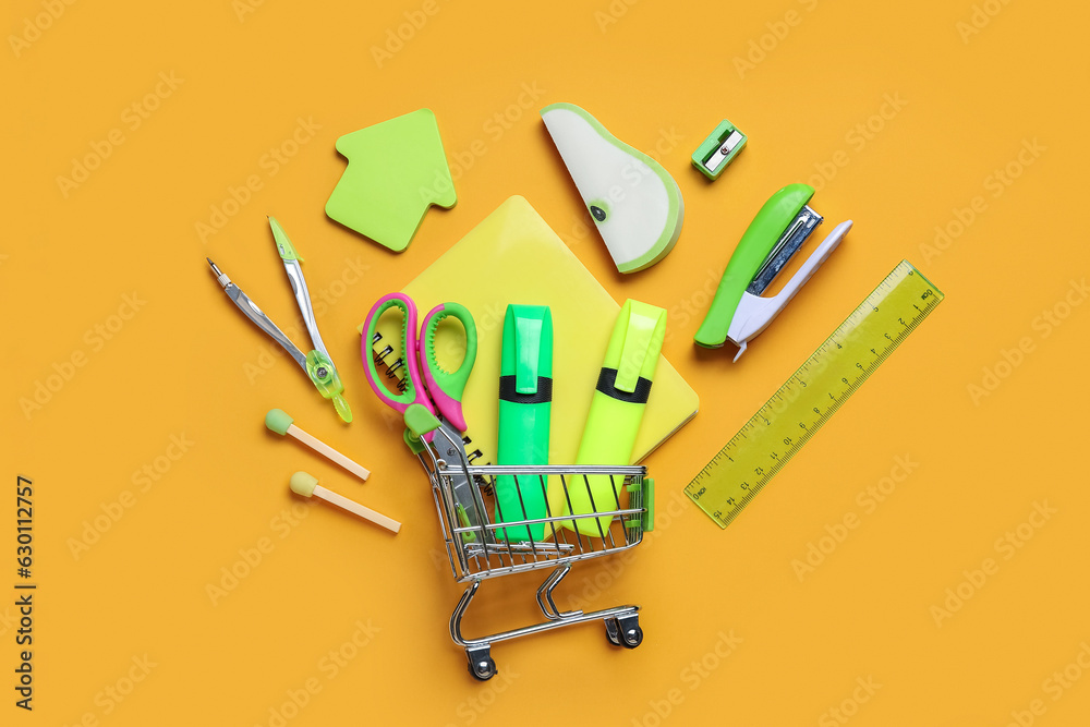 Composition with shopping cart and different stationery on color background