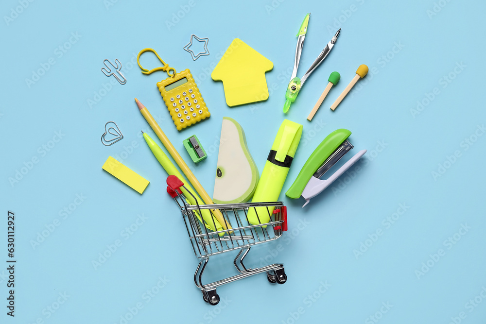 Composition with shopping cart and colorful stationery on color background