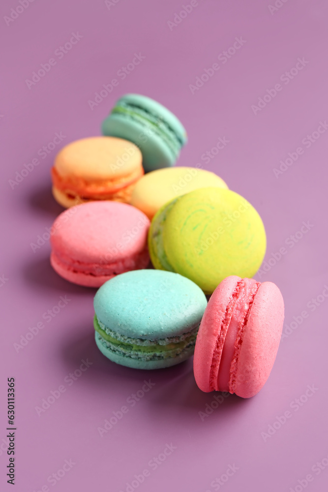 Different tasty sweet macaroons on purple background