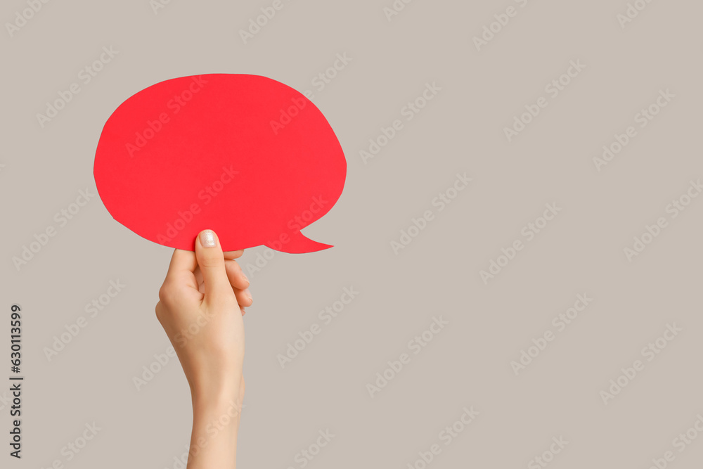 Female hand with speech bubble on grey background