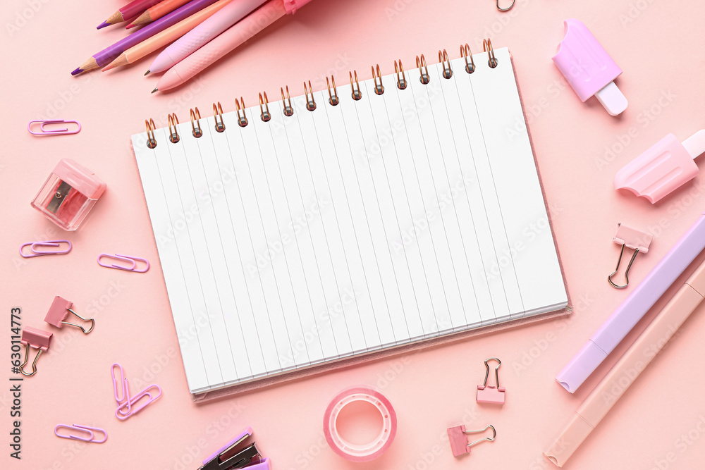 Notebook with different stationery supplies on pink background