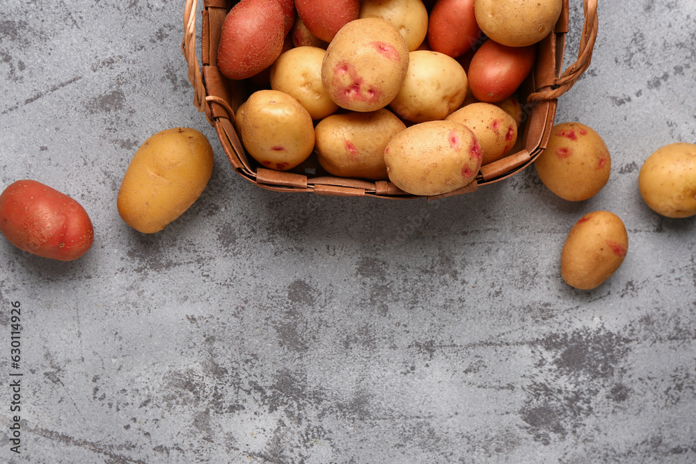 Wicker basket with fresh raw potatoes on blue background