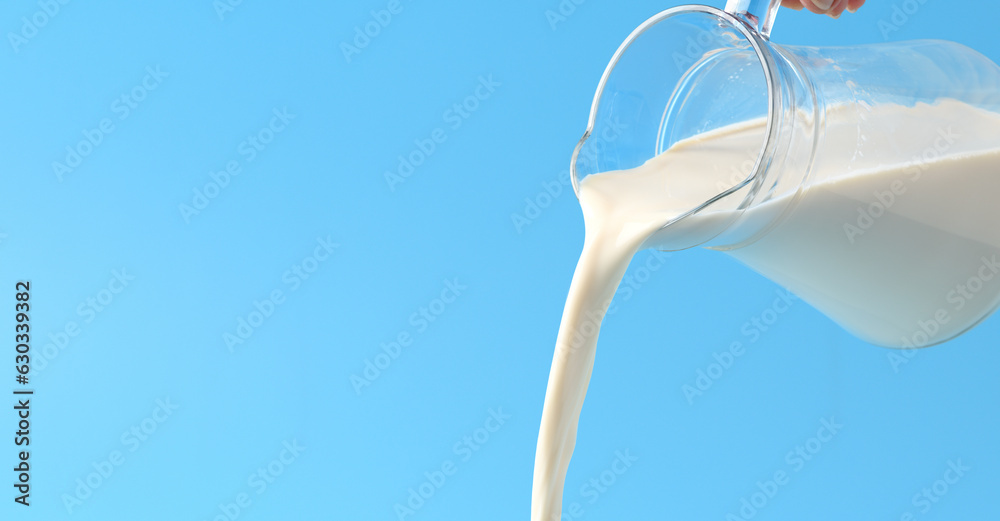 Pouring fresh milk with light blue background.