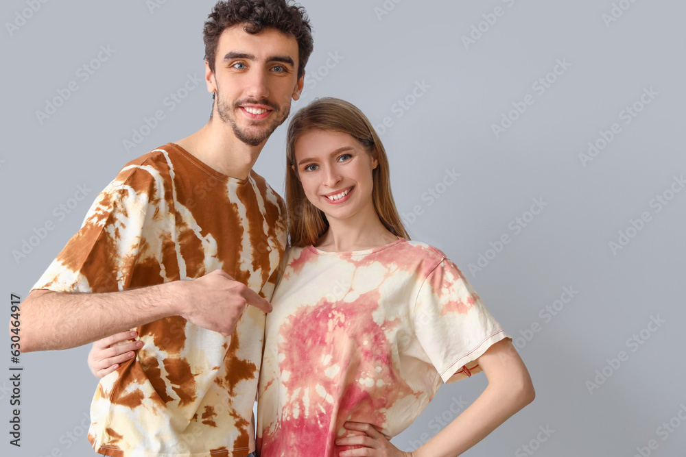 Young couple in tie-dye t-shirts on light background