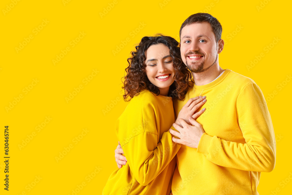 Happy young couple hugging on yellow background