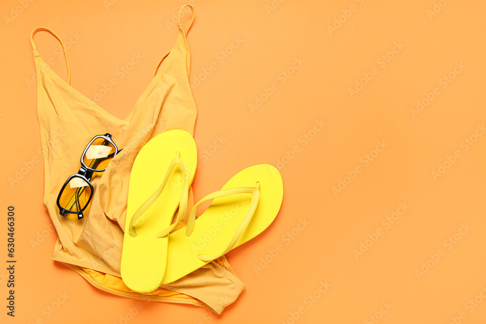 Flip-flops with sunglasses and swimsuit on red background