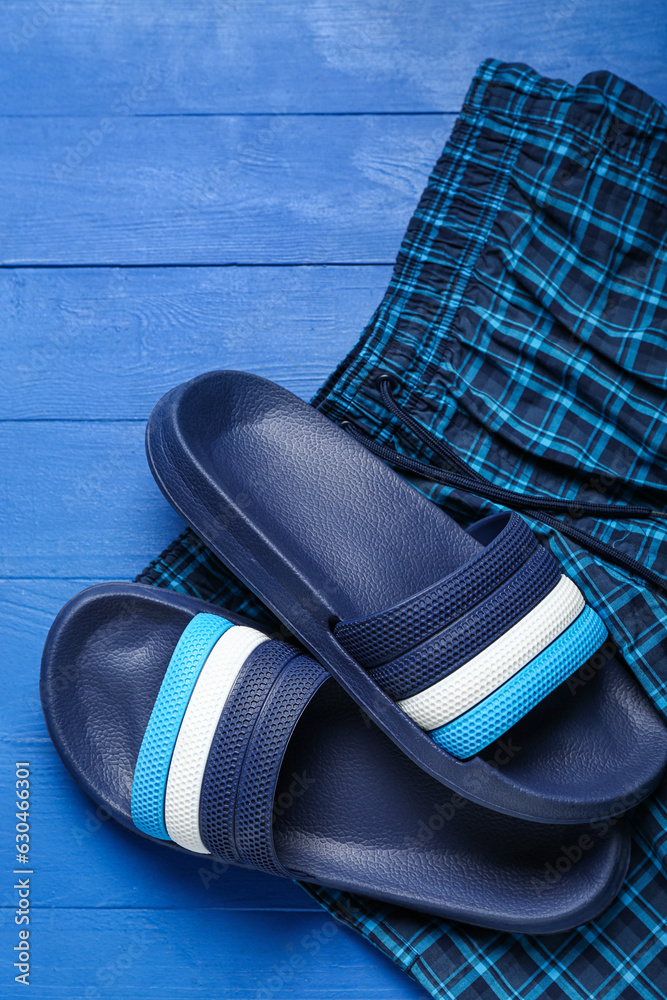 Flip-flops with shorts on blue wooden background