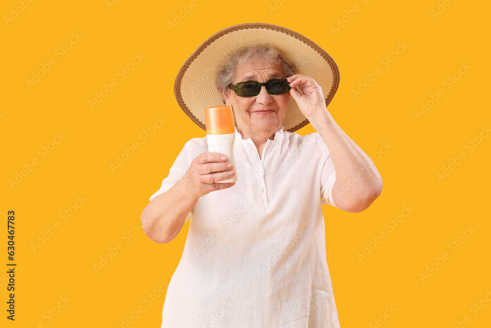 Senior woman with sunscreen cream on orange background