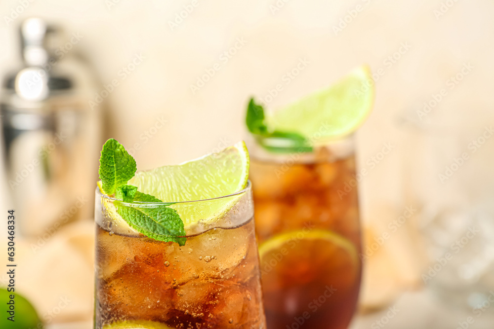 Glasses of cold Cuba Libre cocktail on light background, closeup