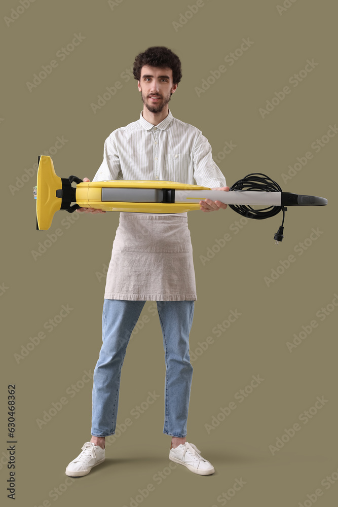 Young man with vacuum cleaner on green background