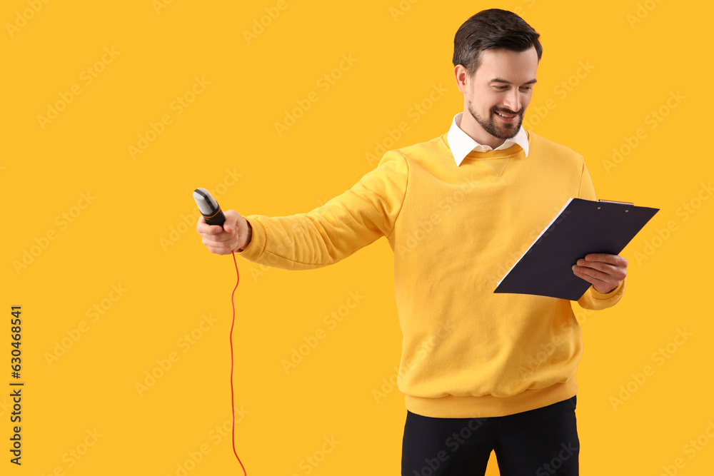 Male journalist with microphone and clipboard on yellow background