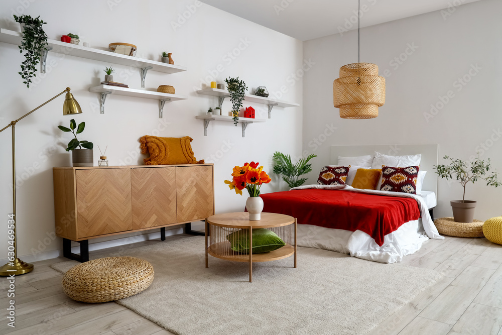 Interior of stylish bedroom with tulip flowers in vase on wooden table