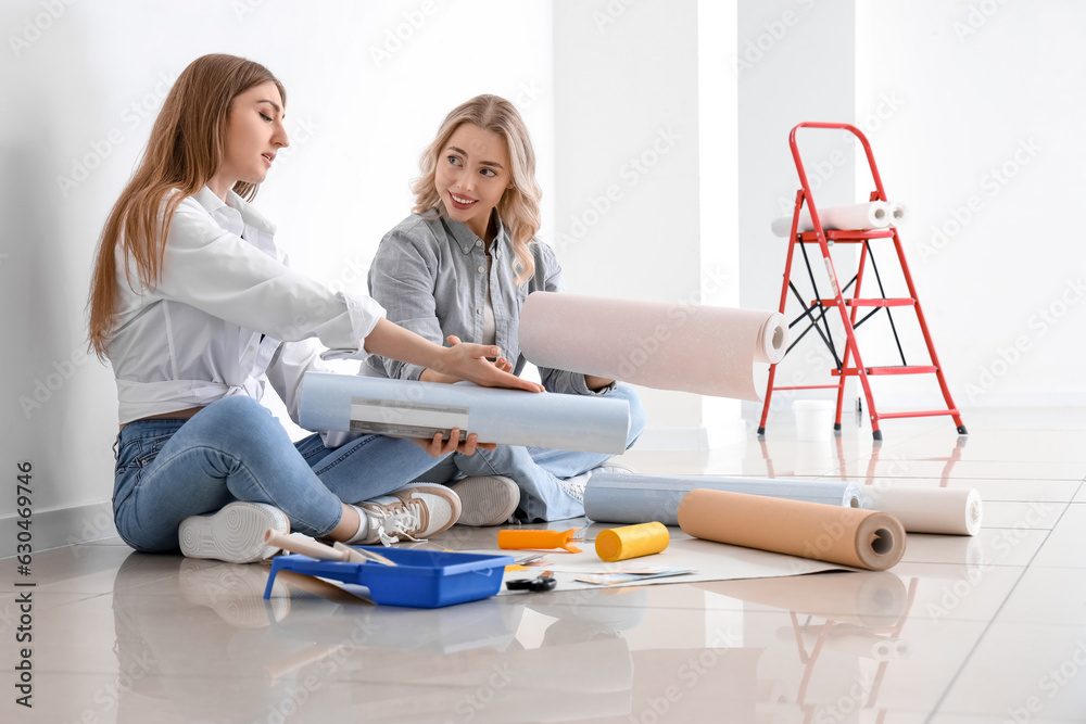 Young women with wallpaper rolls at home