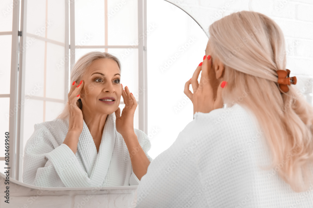 Mature woman looking in mirror at home