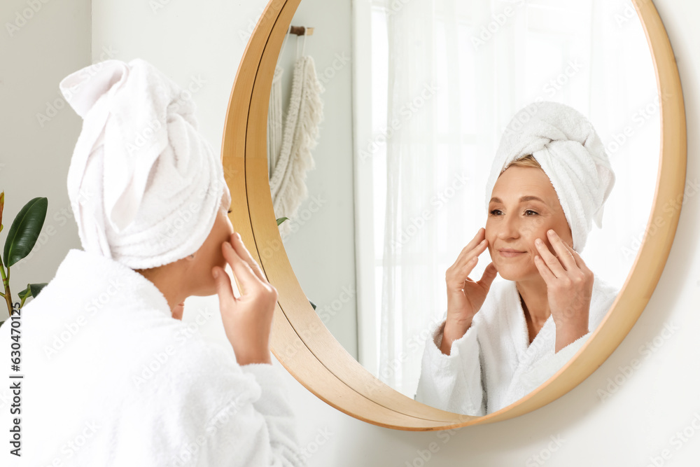 Mature woman looking in mirror at home