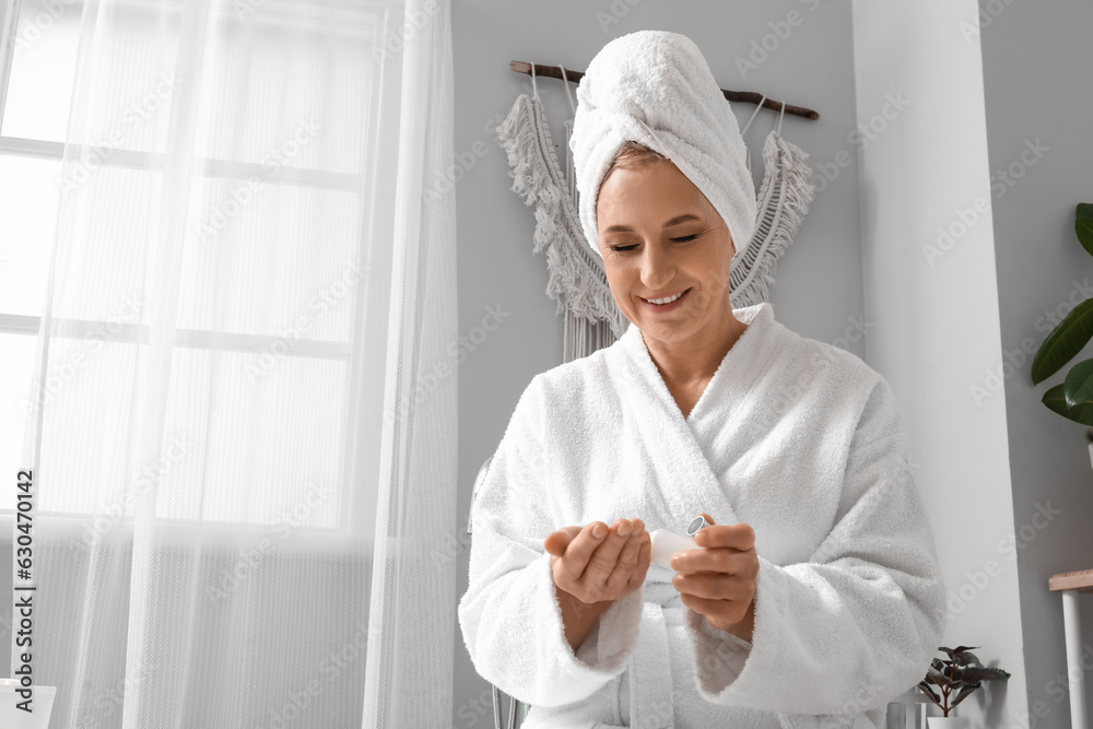 Mature woman applying essential oil in bathroom