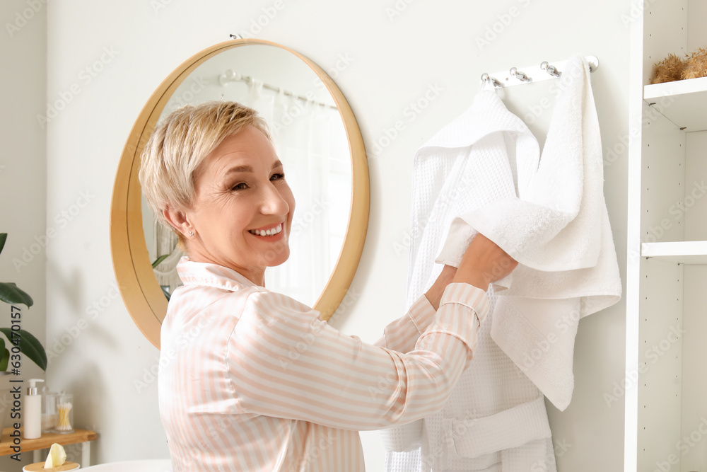 Mature woman wiping hands with towel in bathroom