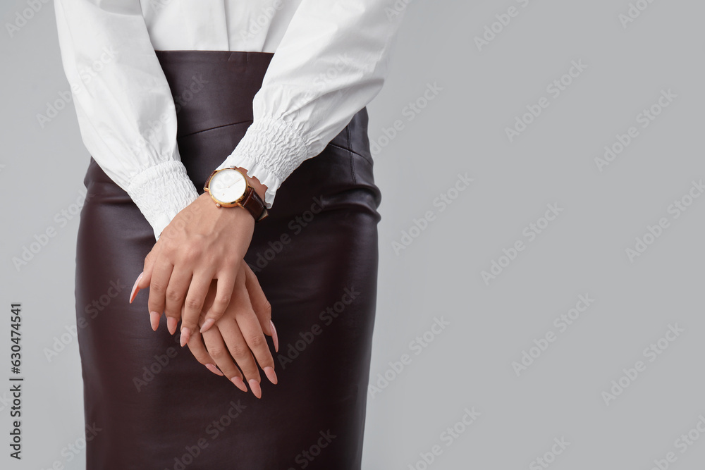 Beautiful young woman with wristwatch on grey background