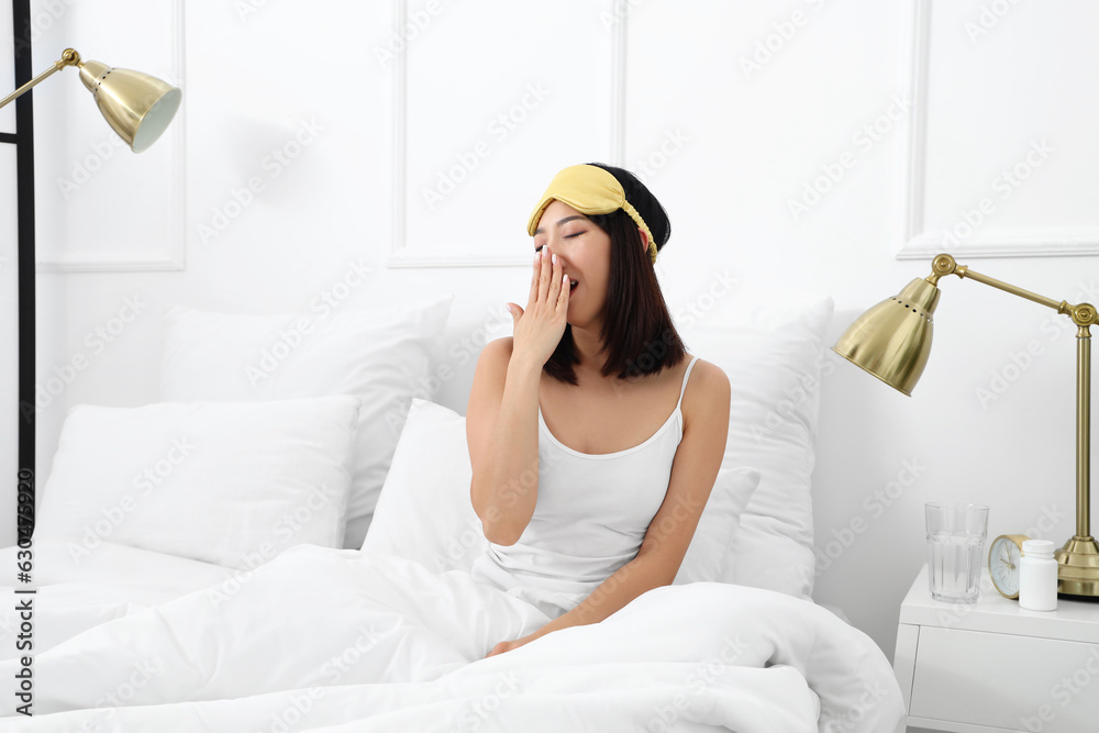 Beautiful Asian woman with sleeping mask in bedroom