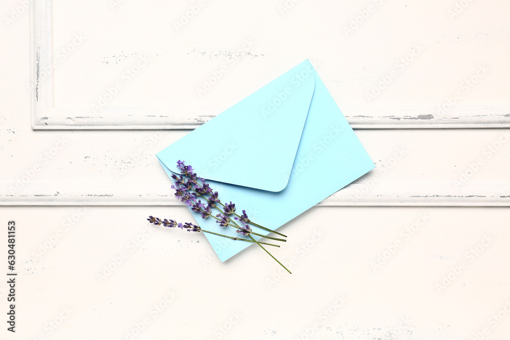 Branches of beautiful lavender flowers and envelope on light wooden background