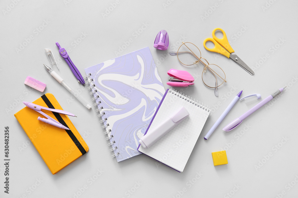 Different school stationery, notebooks and glasses on grey background