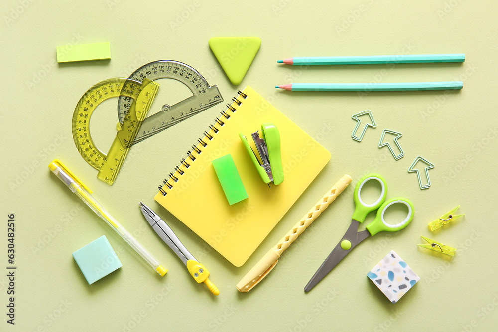 Different school stationery and notebook on green background