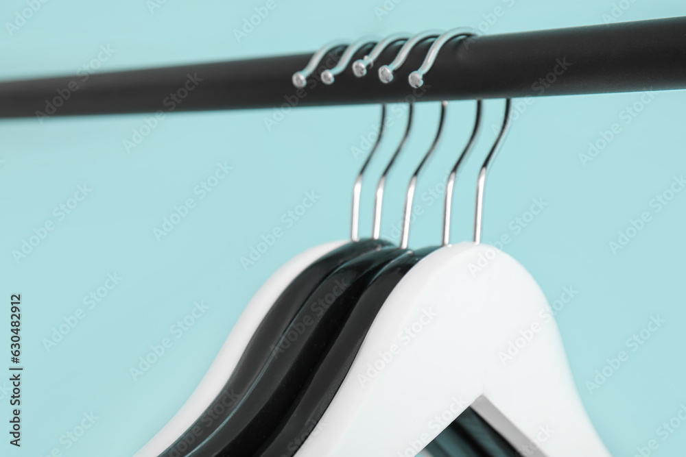 Rack with wooden clothes hangers on blue background