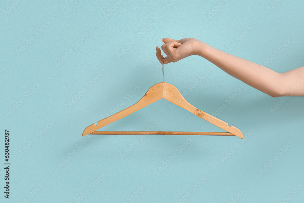 Woman holding wooden clothes hanger on blue background