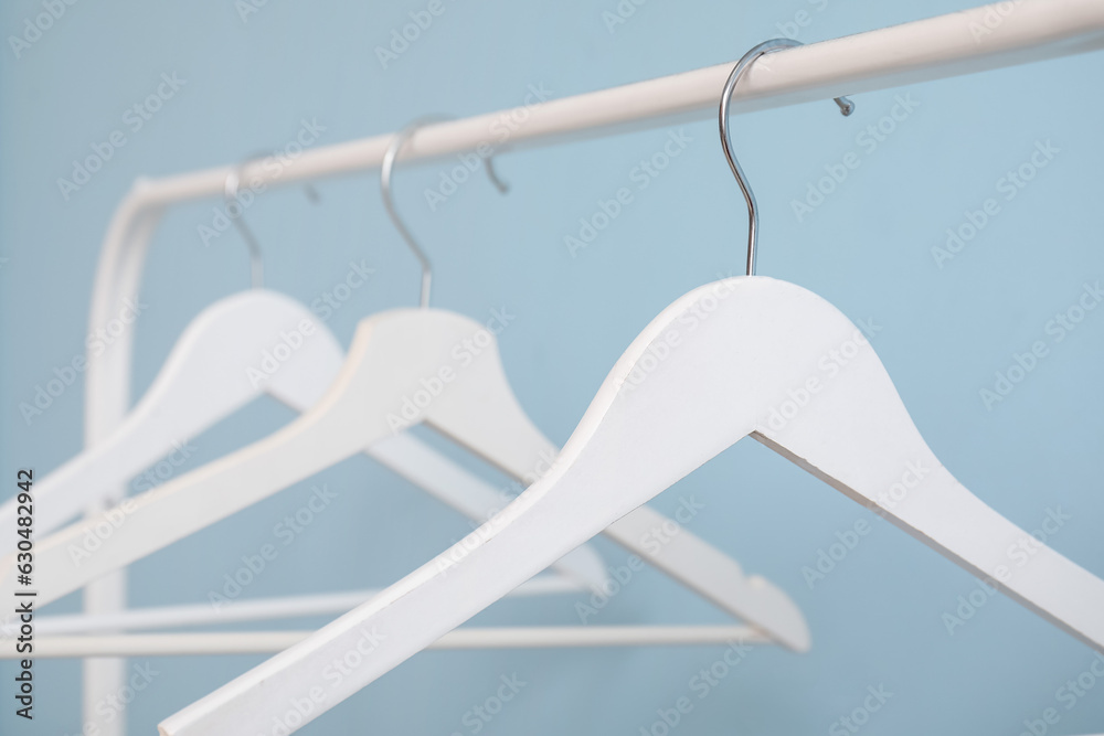 Rack with wooden clothes hangers on blue background