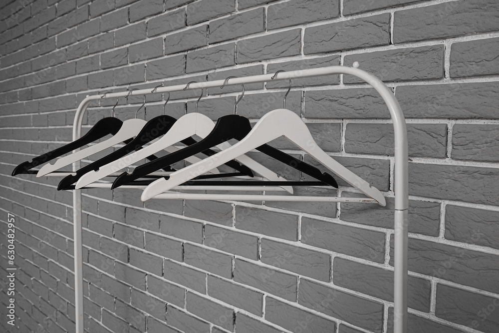 Rack with wooden clothes hangers on grey brick wall background