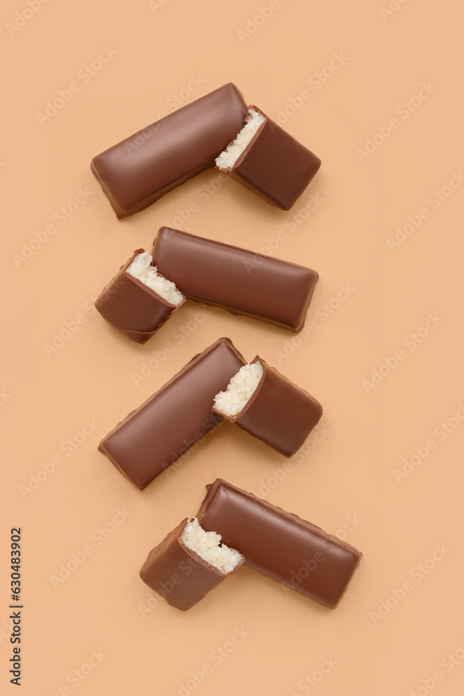 Tasty chocolate covered coconut candies on yellow background