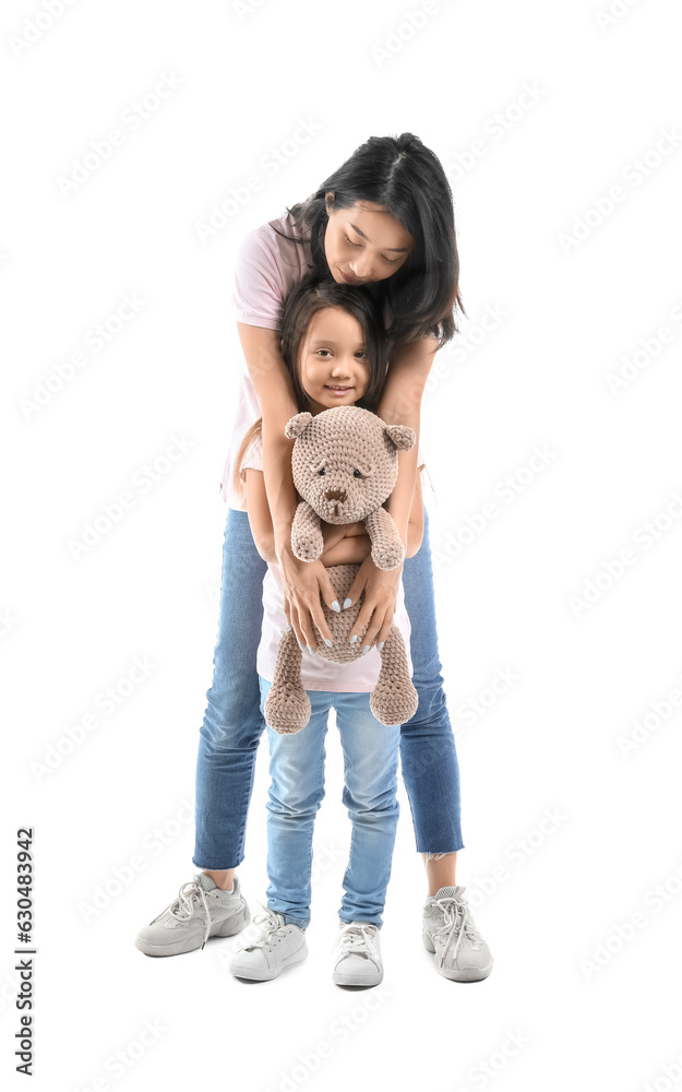 Asian mother with her little daughter and toy bear on white background