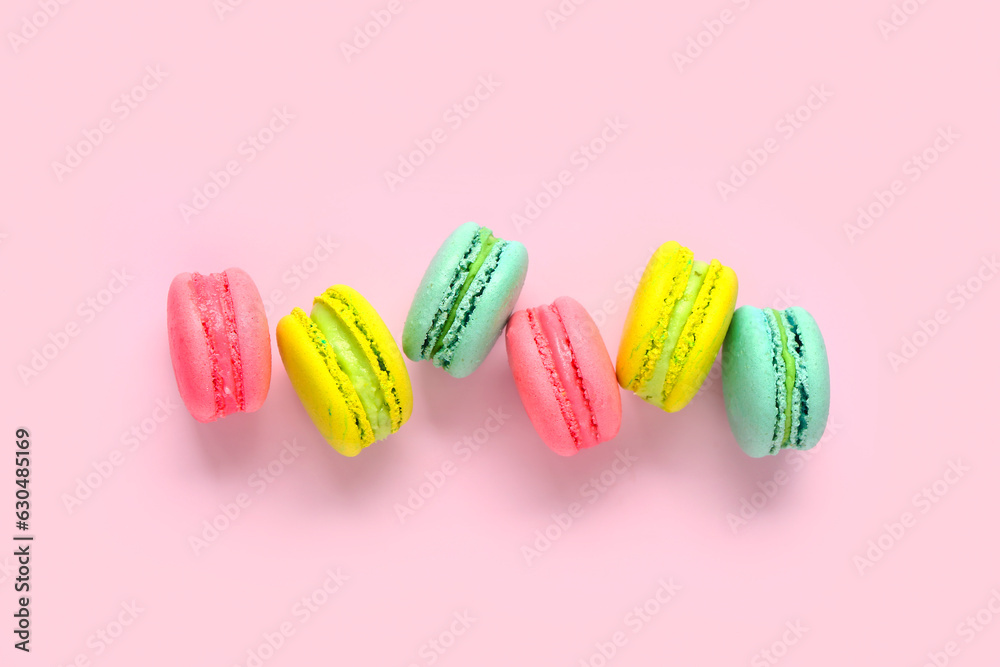 Different tasty sweet macaroons on pink background