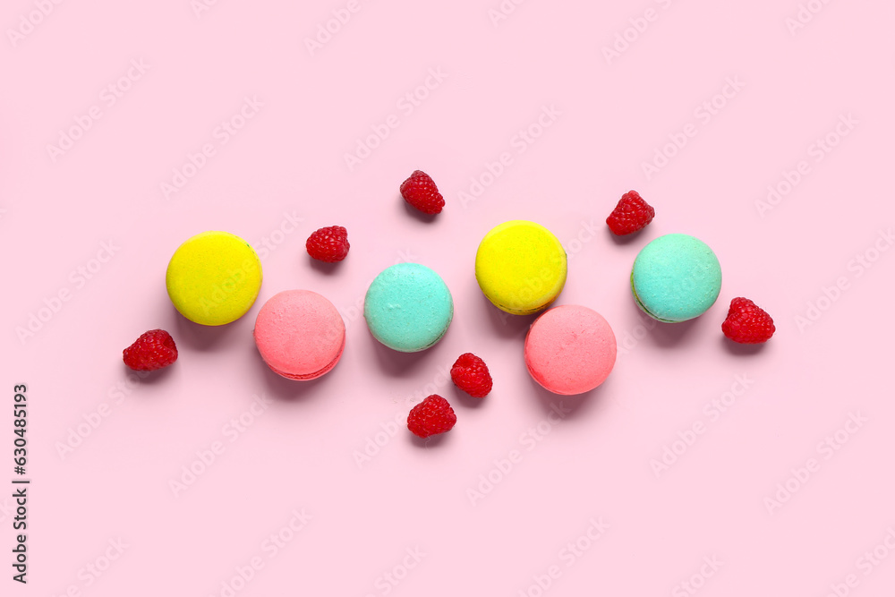 Different sweet macaroons and raspberries on pink background