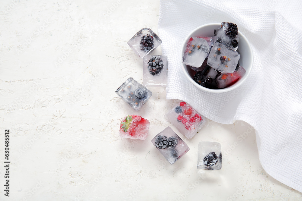 Bowl with frozen berries in ice cubes on white background