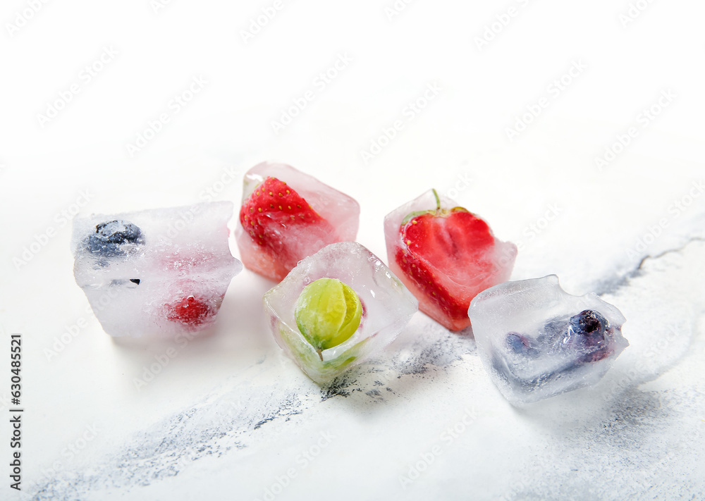 Frozen berries in ice cubes on white background