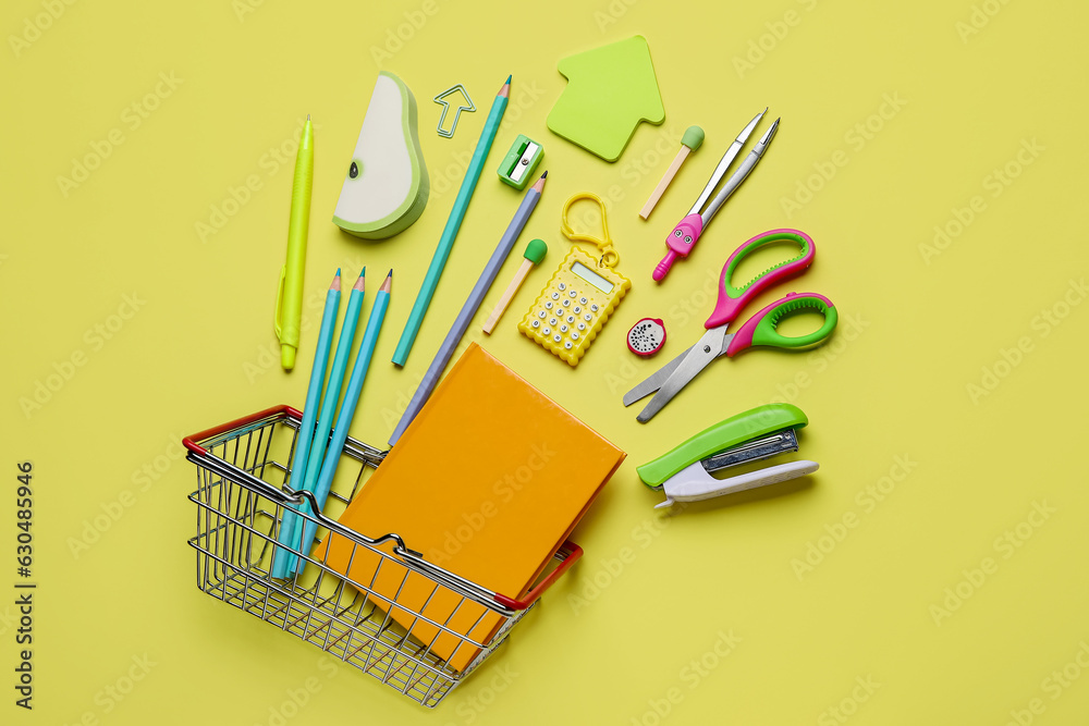 Shopping basket with different school stationery on yellow background