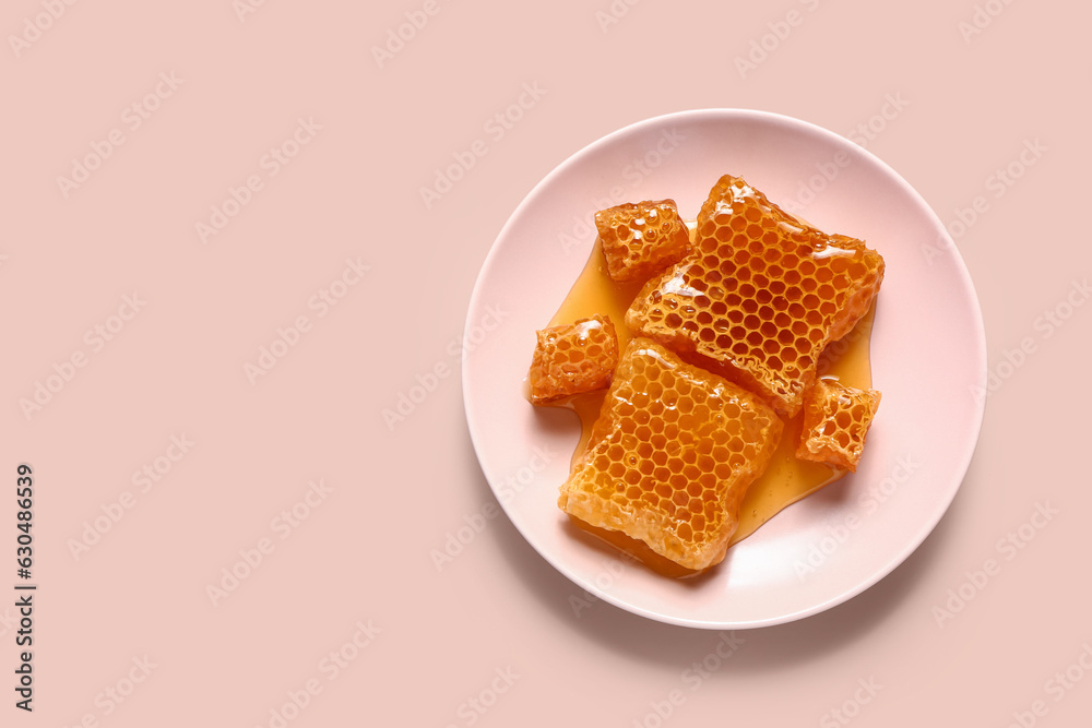 Plate with sweet honeycombs on pink background