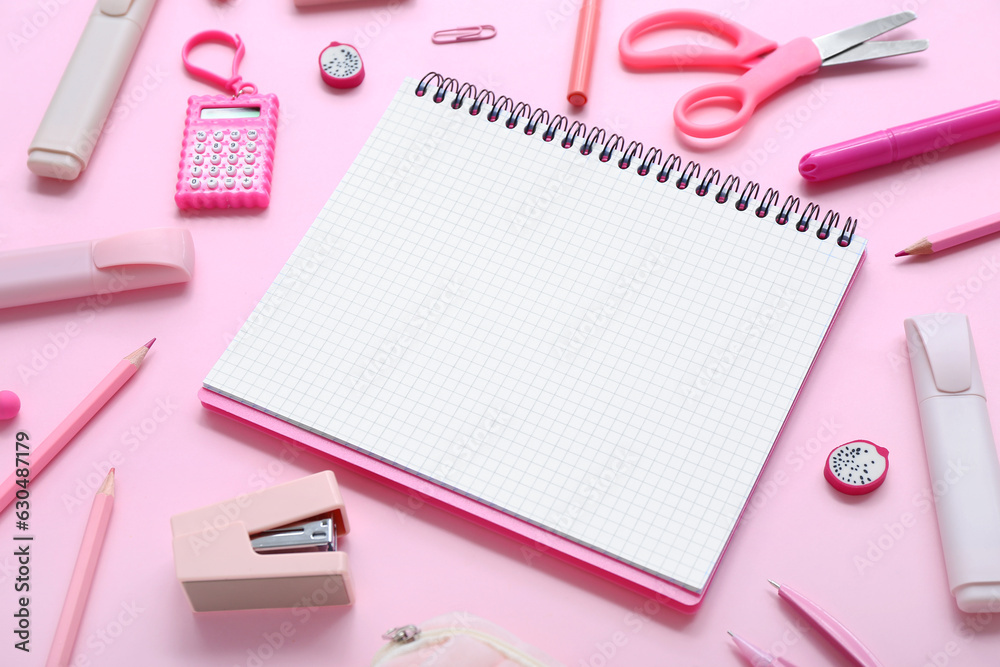 Notebook with different stationery supplies on pink background