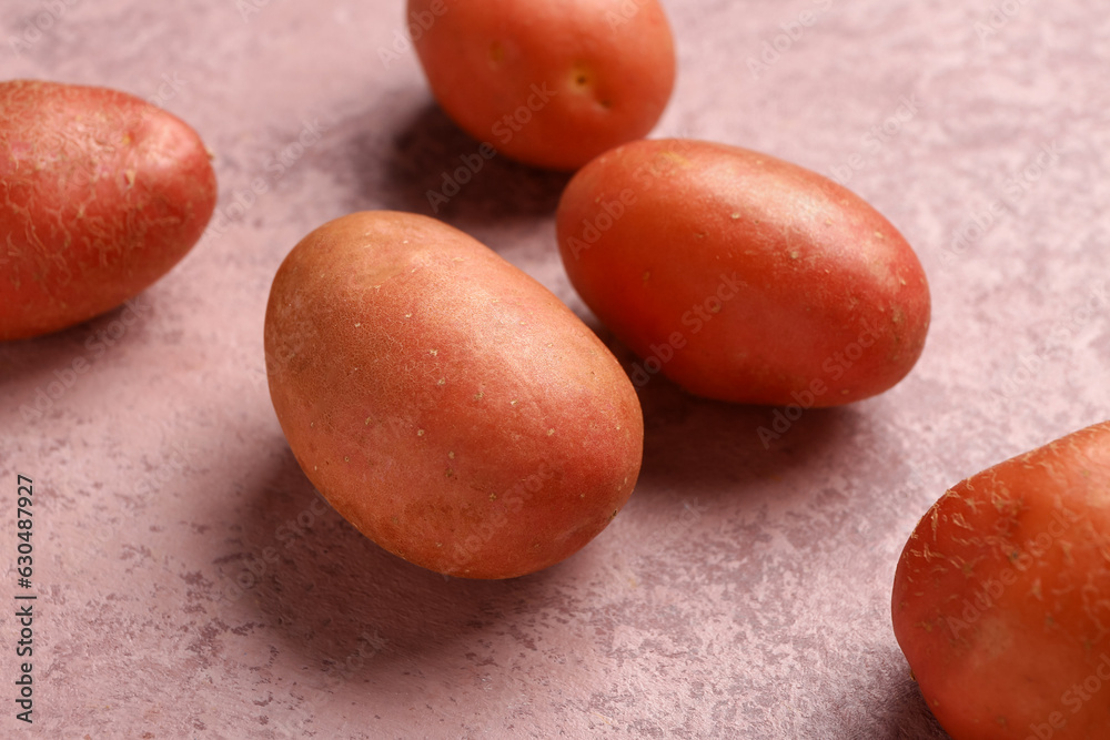 Fresh raw potatoes on pink background