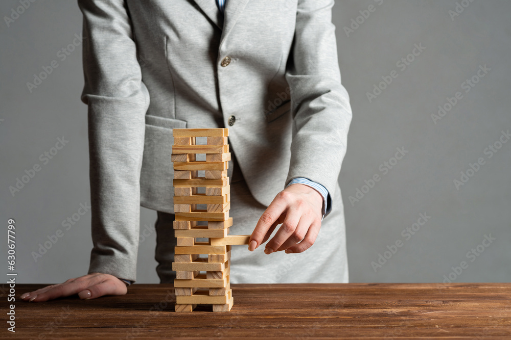 Businesswoman removing wooden block from tower