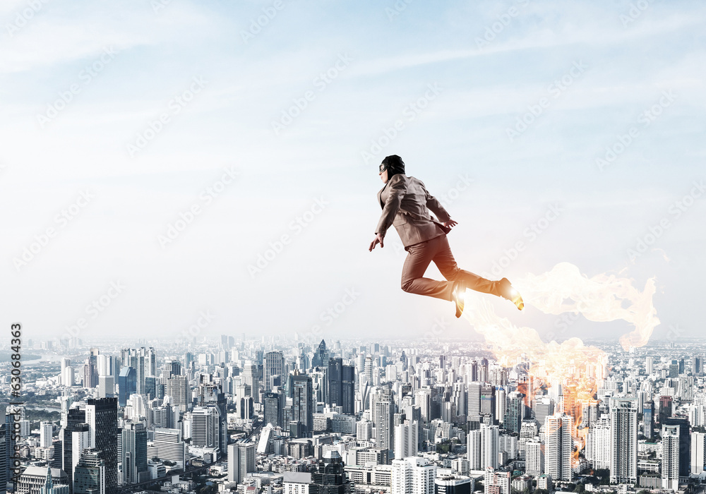 Businessman in suit and aviator hat flying in sky